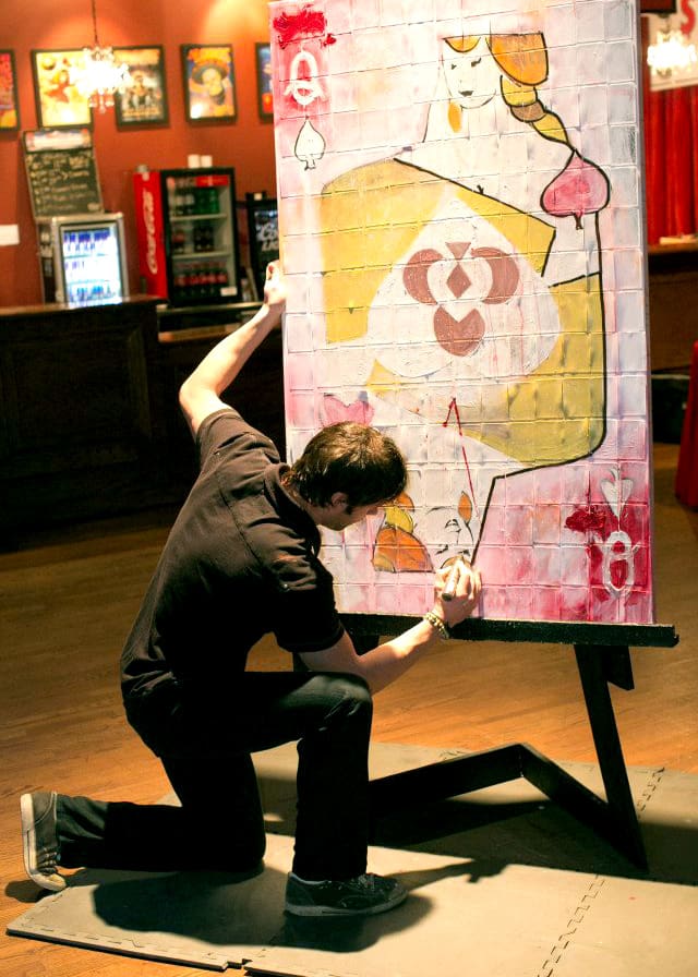 An artist painting a giant playing card