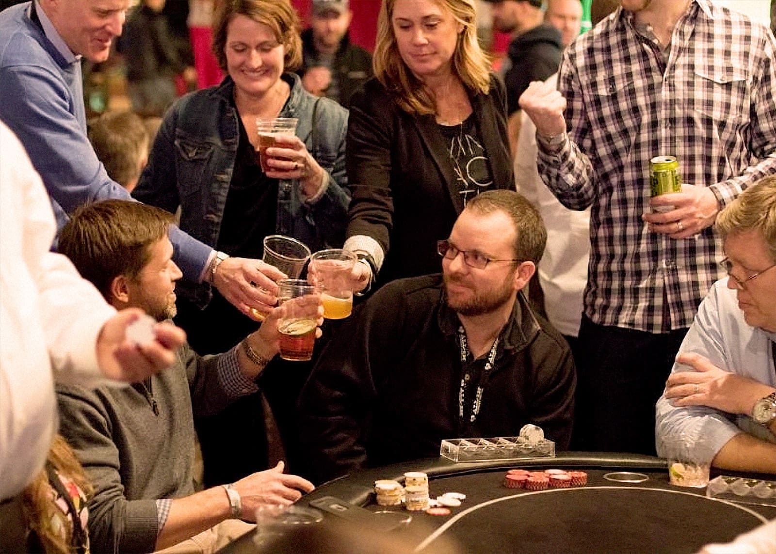 A group of people toasting their drinks around a card table