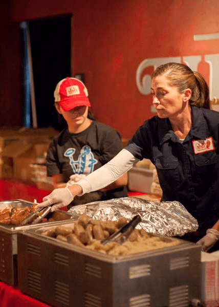 Two people serving food at an event