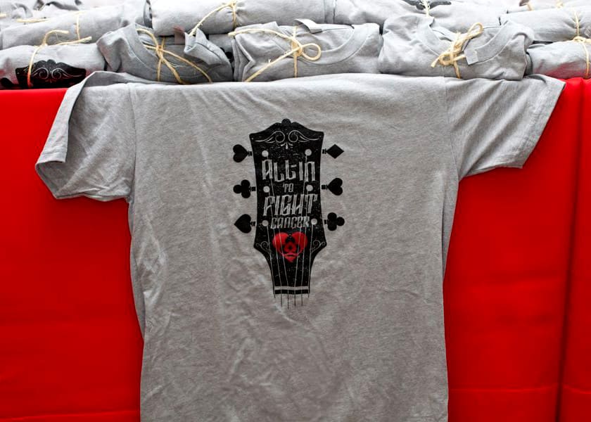 A shirt with a guitar headstock that says: All-In to Fight Cancer