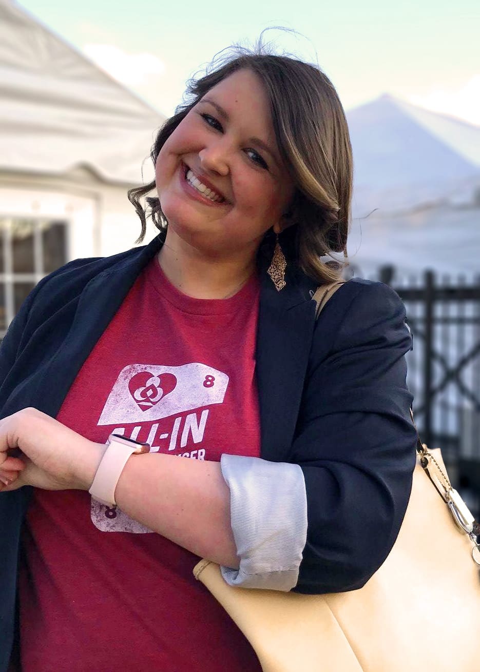 A smiling woman in a pink All-In shirt