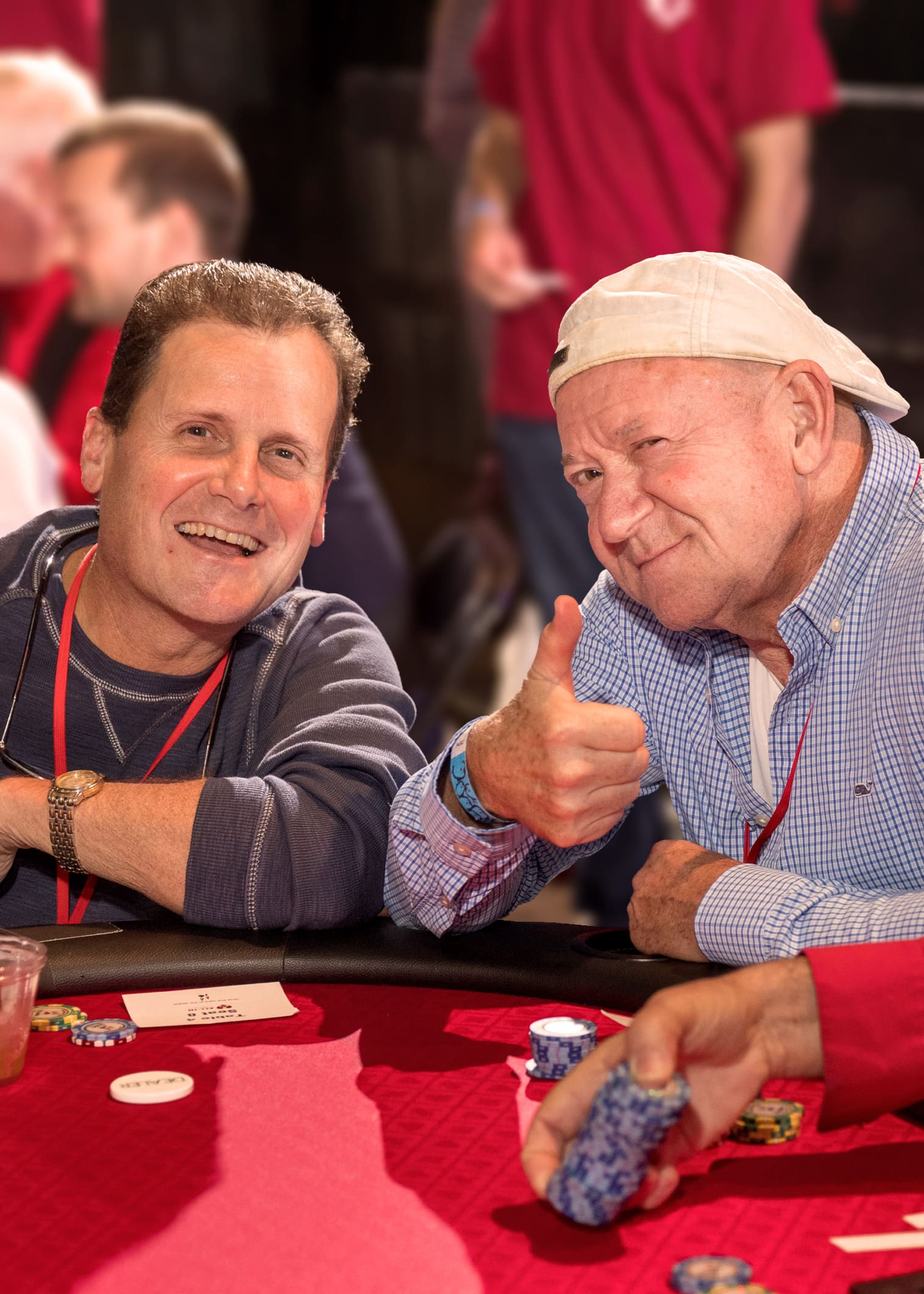 Two men at a card table. One of them is giving a thumbs-up.